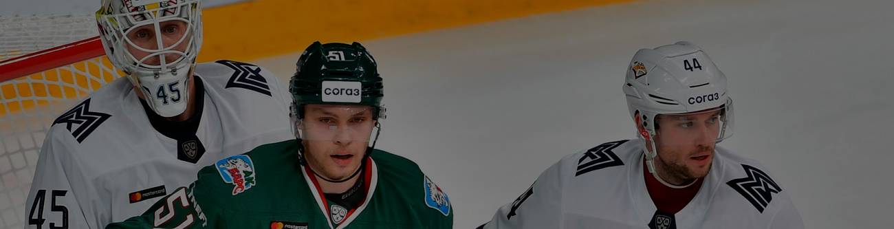 На изображении трое хоккеистов в игровой форме на льду. Один в зелёной форме, двое других в белой. Видны шлемы, защитные элементы и хоккейная сетка на заднем плане